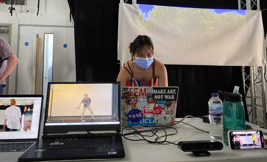 Chelly Jin at her laptop at Choreographic Coding Lab 14 with various screens visible in front. (Also on screens: Irini Kalaitzidi, Mark Coniglio, me and Allison Costa.) Photo by Tim Murray-Browne.