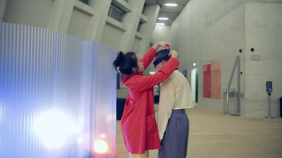 A video still showing the Movement Alphabet host putting a blindfold on the participant. Taken from a film created by Mind The Film of Movement Alphabet by Jan-Ming Lee and Tim Murray-Browne