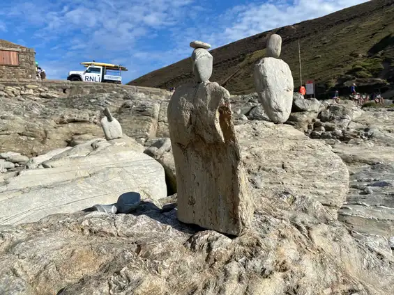 A photo of rocks stacked into human figures on a beach, taken by Tim Murray-Browne.